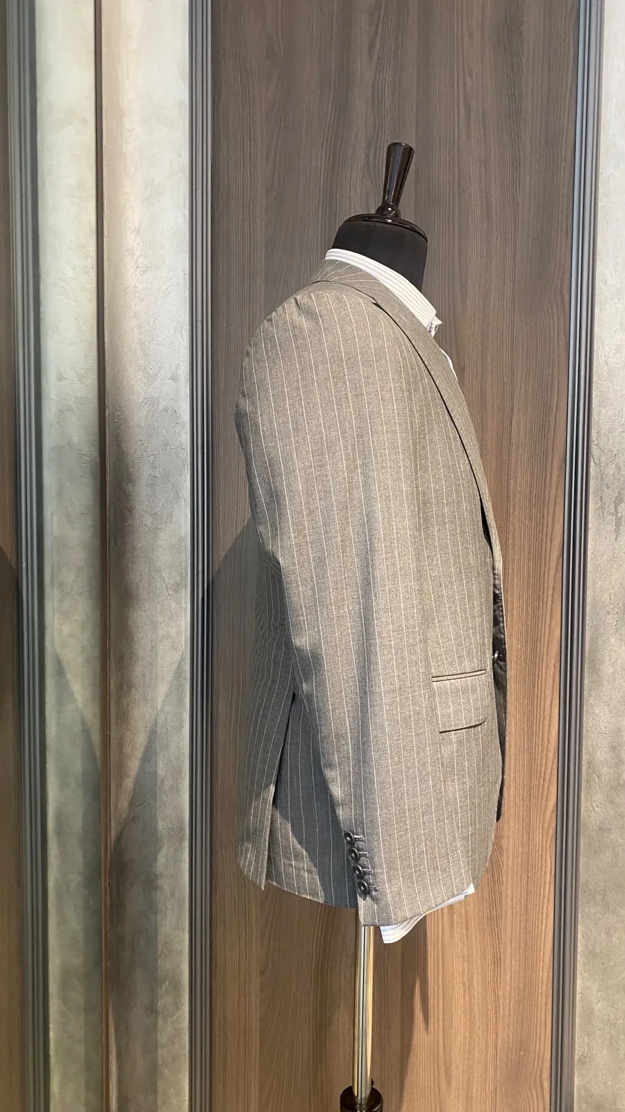 Side view of grey pinstripe jacket showing sleeve buttons and side vent